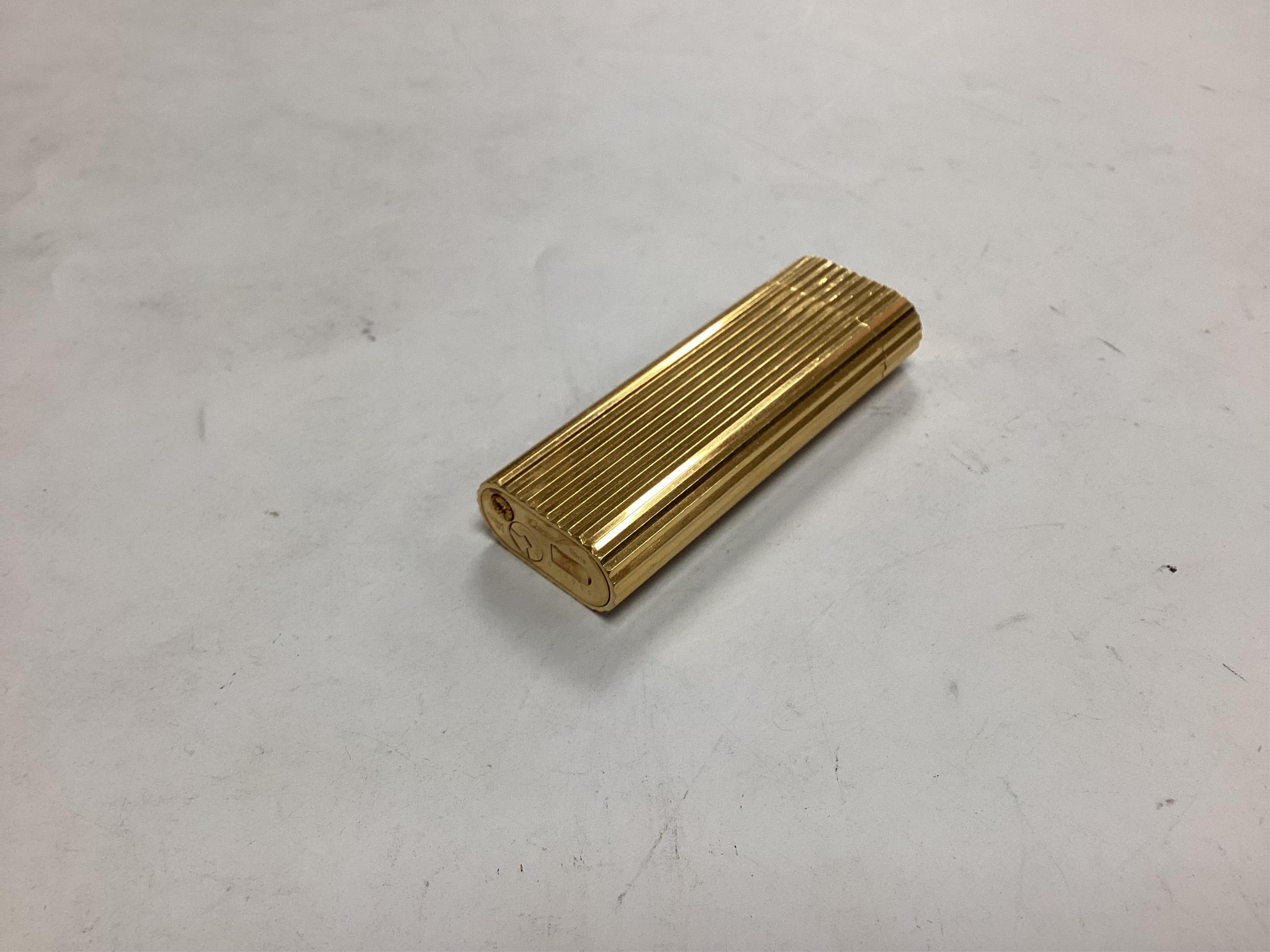 A Cartier lighter, in red suede pouch